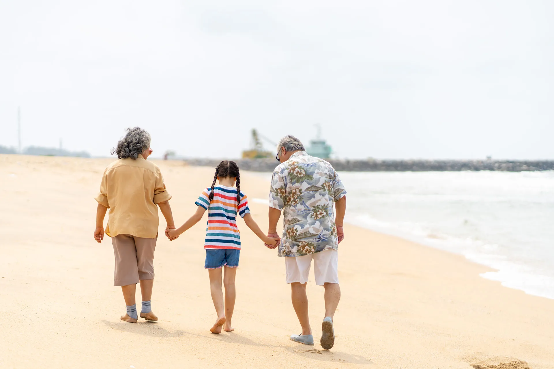 Grandparents and Grandchild Girl Enjoy Outdoor Walking Together at Tropical Island Beach in Sunny Day